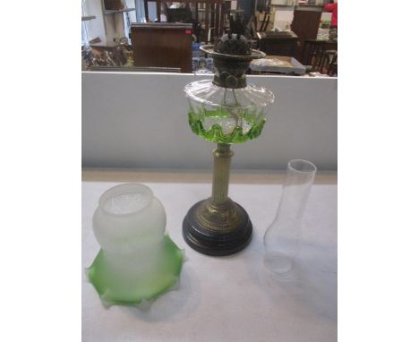 A Victorian gilt brass column oil lamp with clear glass reservoir having applied green trailing, one black glazed pottery bas