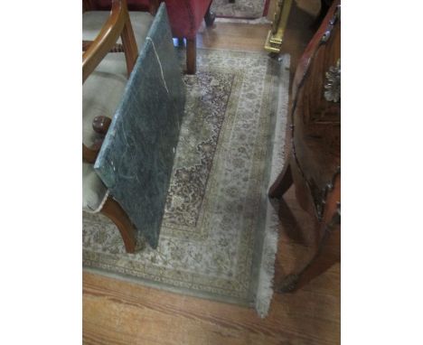 A WOOL RUG the light green and beige ground with central floral panel within a conforming border 238cm x 158cm