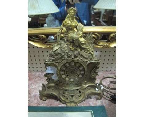 A FRENCH GILT BRASS MANTLE CLOCK surmounted with a female shown seated holding a wheat of sheaf the dial with Roman numerals 