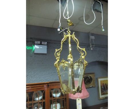 A GILT BRASS SINGLE LIGHT HALL LANTERN with glazed panels on scroll arms 88cm drop