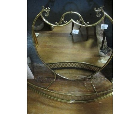 A BRASS AND MIRRORED FIRESCREEN of shield shaped outline with carrying handle raised on splayed legs 77cm (h) x 60cm (w)