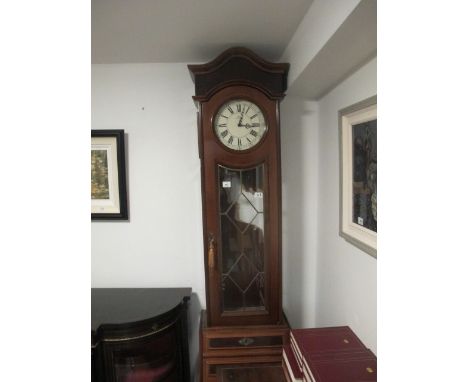 A MAHOGANY LONG CASE CLOCK the arched pediment above a circular dial with Roman numerals and astragal glazed door the base wi