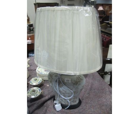 A PORCELAIN TABLE LAMP of ovoid form the light blue ground with floral decoration raised on an ebonised stand with pleated sh