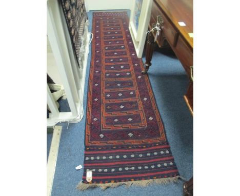 A KILIM AFGHANISTAN HANDMADE RUNNER the indigo and wine ground with central medalions within a two stripe border 276cm x 59cm