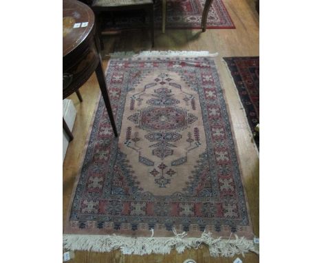 A PAKISTAN WOOL RUG the light pink and beige ground with central panel with palmets and stylized flowerheads within a four st