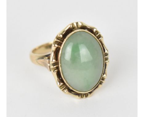 A 9ct yellow gold mounted green jade dress ring, the central oval cabochon stone in a bezel mount with bamboo style setting, 