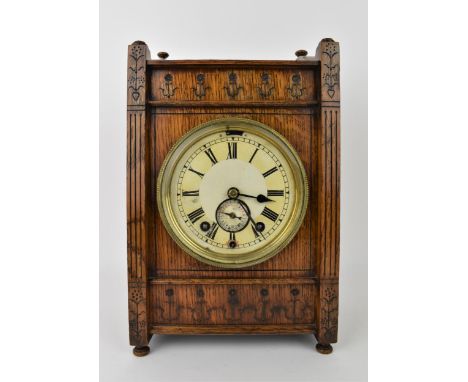 An early 20th century oak mantle clock, the case having turned finals to the top, floral carved decoration with fluted column