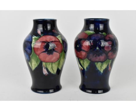 A pair of Walter Moorcroft ceramic baluster vases in the 'Pansy' pattern with pink and purple glazed tubelined pansies on a d