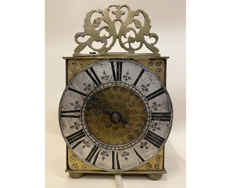 A brass cased lantern single hand clock having a 6" silvered chapter ring with Roman numerals with pierced finial to the top 