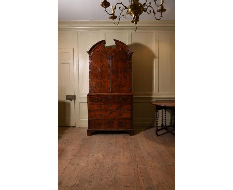 A George I walnut and featherbanded secretaire cabinet, circa 1720, the divided domed top above a pair of arched doors, openi