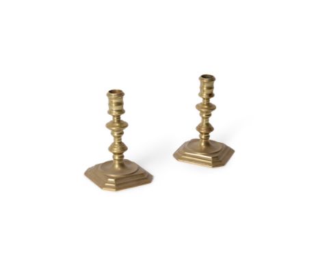 A pair of Queen Anne brass candlesticks, first quarter 18th century, the knopped stems descending to moulded and canted squar