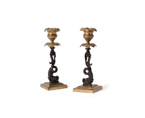 A pair of Regency gilt and patinated bronze candlesticks, circa 1815, each foliate cast nozzle raised on a dolphin stem, 18.5