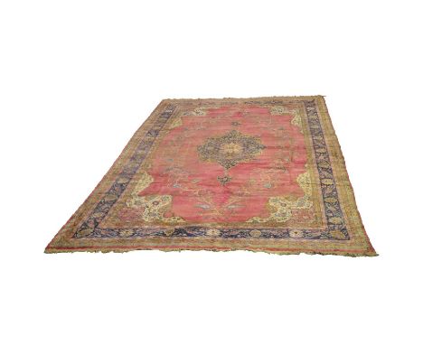 Large Tabriz carpet, central medallion against a pale pink ground, enclosed by cream spandrels and blue borders, heavily worn