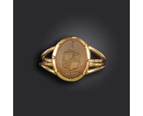 A carnelian intaglio gold signet ring, the oval-shaped carnelian engraved with arms, crest and motto, in cut-down collet moun