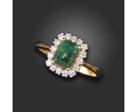 An emerald and diamond cluster ring, set with an emerald-cut emerald within a surround of round brilliant-cut diamonds in gol