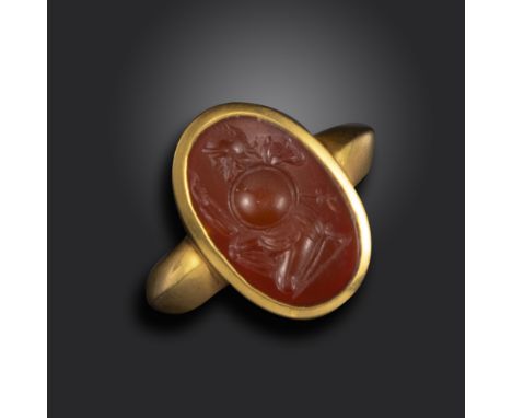 A Roman carnelian intaglio depicting a kneeling warrior, c1st century BC - 1st century AD, the warrior wearing a helmet with 