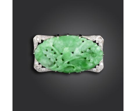 A jade and diamond plaque brooch, set with a carved oval jadeite panel depicting flowers quartered with stylised diamond tref
