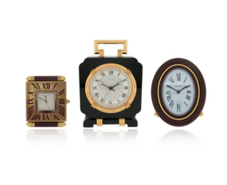 Three travel clocks by Cartier, including a Must de Cartier brass and red enamel travel alarm clock, with signed square white