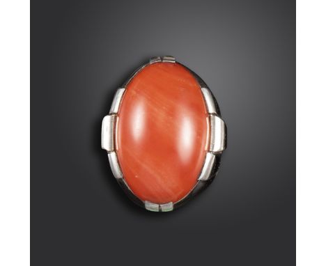 λ A French Art Deco coral-mounted silver ring, the oval-shaped coral cabochon is set in a raised tapered slat-form silver rin