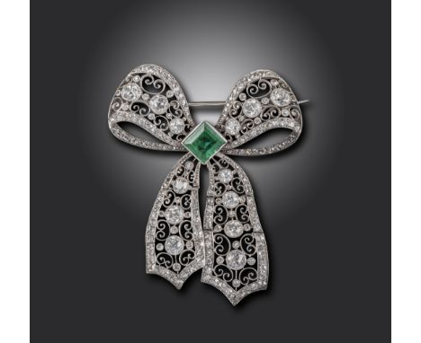 A Belle Epoque emerald and diamond bow brooch, the square emerald set within stylised pierced and scrolling ribbons set with 