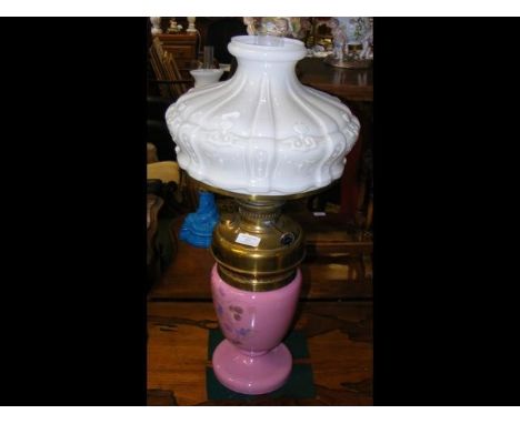 A floral decorated pink glass oil lamp with embossed milk glass shade