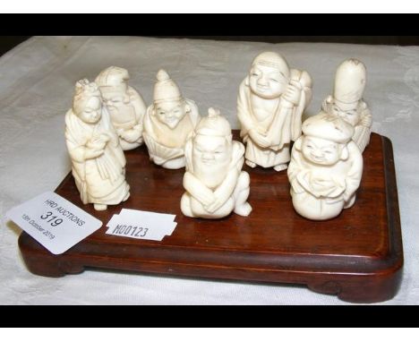 Seven Japanese carved ivory figures on wooden stand 