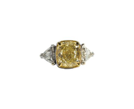 European Circa 2000 An impressive cushion-shaped yellow diamond and white diamond three-stone ring The central cushion-shaped