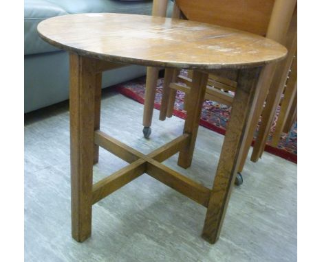 A mid 20thC light oak occasional table, raised on rectangular legs with crossover stretchers  bears a Utilty mark  16''h  16'