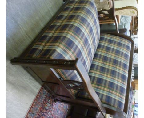 A 1920s panelled and stained oak bed settee, having a high, level back and arms with carved splats, upholstered in multi-colo