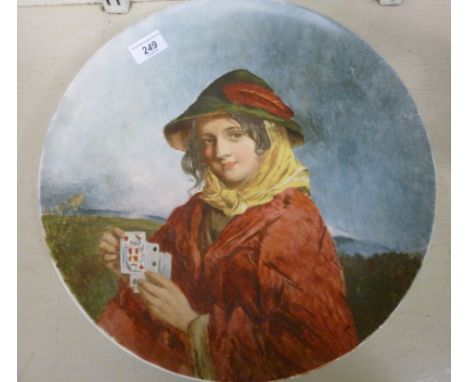 An early 20thC pottery dish, decorated with a study of a young girl holding playing cards  15''dia        TOS9