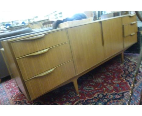 A modern Nathan teak sideboard, the pair of central, full height doors flanked by six graduated short drawers, on tapered leg