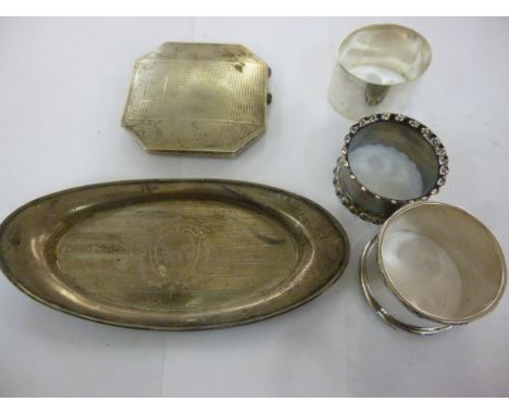 Silver, viz. three napkin rings; an oval, engine turned pin tray; and a square powder compact  mixed marks       11