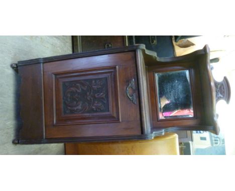 A late Victorian mahogany purdonium with a mirrored upstand on a shelf, over a carved panelled fall front, raised on casters 