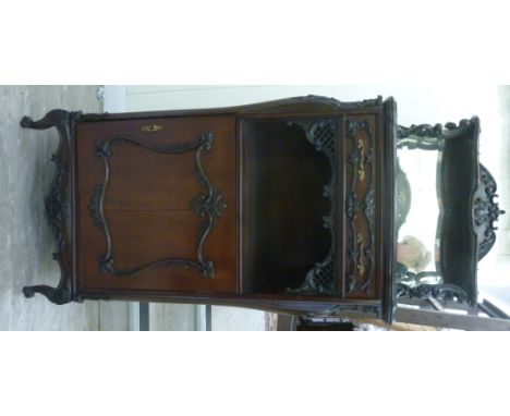 A late Victorian carved mahogany music cabinet, the bevelled mirror panelled superstructure with a shallow shelf on supports,