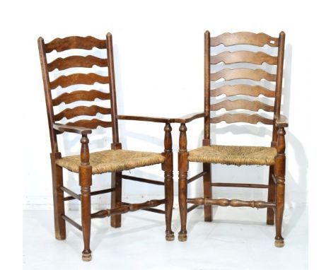 Pair of early 20th Century beech ladder back open arm elbow chairs, each having a rush seat and standing on tapered pad suppo