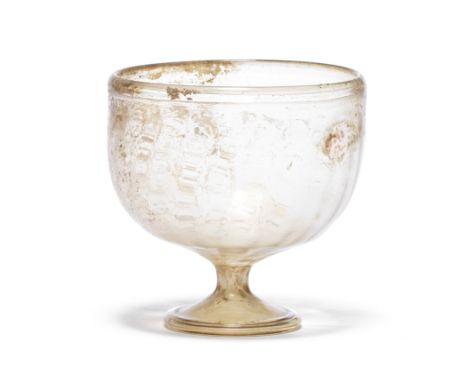  A Roman pale olive-brown glass goblet Circa 4th-5th Century A.D.The bowl with moulded vertical ribbing, set on a short hollo