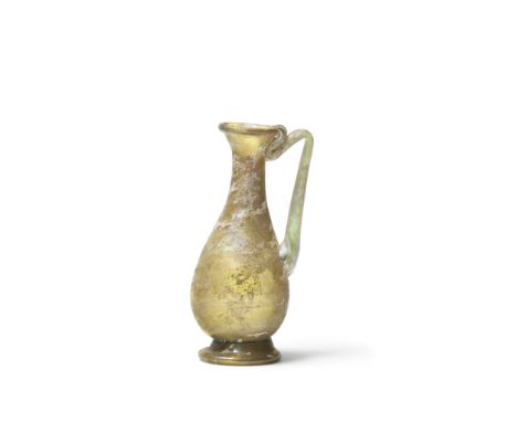  A Roman yellow glass jug  Circa 4th Century A.D.With flared mouth and infolded rim, the piriform body set on a tooled raised