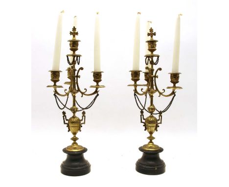 A pair of bronze table candelabra, each with a black marble base, vase column, hanging chains and three sconces. 48cm highCon