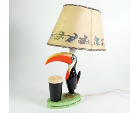 CARLTONWARE CHINA, GUINNESS TOUCAN ADVERTISING TABLE LAMP WITH ORIGINAL PRINTED SHADE, modelled as a toucan with a pint of Gu