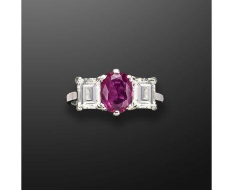 A ruby and diamond three-stone ring, the oval-shaped ruby set with a baguette-shaped diamond to each shoulder in platinum, si