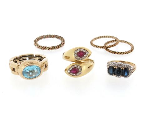 A collection of six rings, including a ruby and diamond-set gold snake ring, a blue topaz-set gold ring with tank-track shank