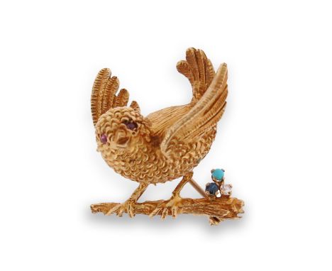 A gold bird brooch, the small bird flapping it's wings and set with ruby eyes and perched on a branch which is set with a tur