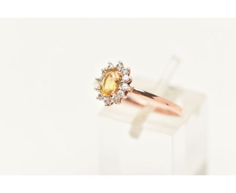 A 9CT ROSE GOLD CLUSTER RING, of an oval form set with an oval cut yellow stone in a surround of colourless topaz, to the pol