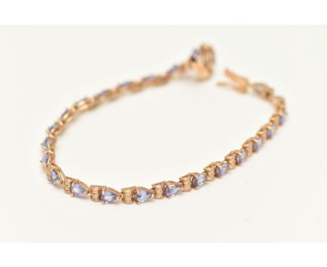 A 9CT GOLD TANZANITE LINE BRACELET, set with a row of pear cut tanzanite each in three claw settings, interspaced with barrel