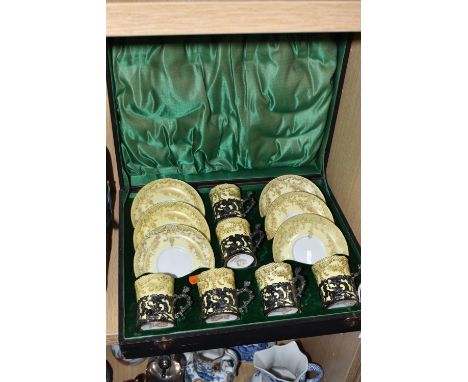 A CASED SET OF SIX CROWN STAFFORDSHIRE 'EGGSHELL' SILVER MOUNTED COFFEE CUPS AND SAUCERS with a gilt swag pattern on yellow, 