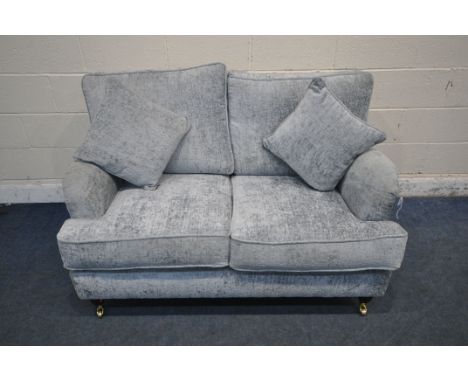 A GREY TWO SEATER SOFA, raised on turned front legs, with brass caps and castors, length 138cm x depth 104cm x height 90cm (c