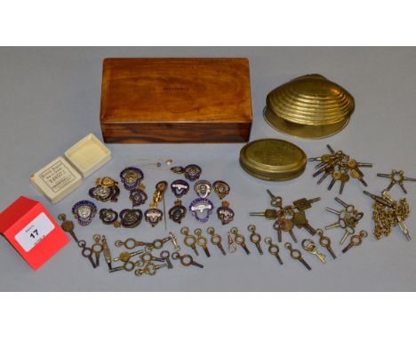 A boxed quantity to include 40+ pocket watch keys, 1908 brass miners snuff box, enamelled British Legion badges, etc.