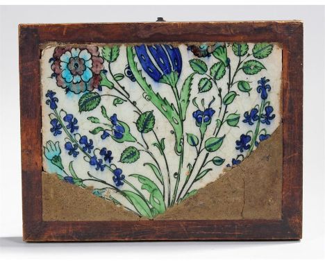 Part Iznik tile possibly 17th Century mounted in a frame decorated with flowers and leaves. 30cm x 23.5cm