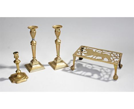 Four brass items to include a pair of classical shaped candlesticks, an 18th Century example and a pierced trivet depicting a