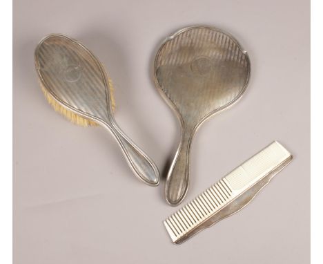 A silver bedroom set. Hairbrush, comb, hand mirror, assayed Birmingham various maker marks.  